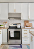 Weiße Küche mit Messingbeschlägen, weißen U-Bahn-Fliesen und Edelstahl-Geräten