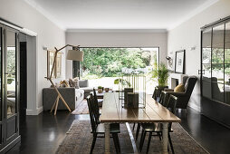 Dining area and lounge in front of open terrace doors in open-plan interior