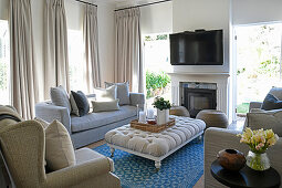 Pale upholstered furniture in front of fireplace and TV
