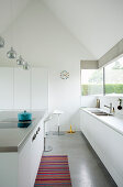 Minimalist, modern kitchen entirely in white below gable roof