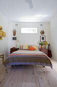 Doppelbett mit gestreifter Bettwäsche und Nachtkästchen im Schlafzimmer