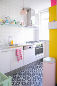 Black-and-white tiled floor in white kitchen with bright accents of bold colour