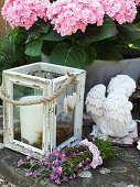 Hydrangea, candle lantern, angel statue and posy of pink forget-me-nots