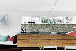 Kitchen counter with pale wooden drawers in base units below narrow ribbon window