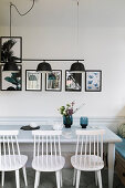 Chairs and benches below black lamps in bright dining area