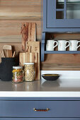 Storage jars and chopping boards in country-house kitchen with blue cupboards