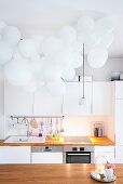 Cloud of white balloons above kitchen island