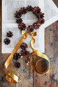 Circle of pine cones and gold ribbon on book pages