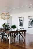 Rustic dining table with chairs in an open living room, black and white photos on the wall