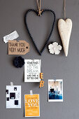 Heart-shaped decorations and postcards with mottoes on grey wall