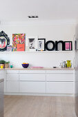 Colourful pictures and decorative letters on picture ledge in modern kitchen