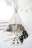 Black-and-white cushions and blanket in wigwam with fairy lights