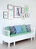 Extendable Swedish bench with flowered cushions under picture gallery
