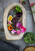 Marigold, vetch, chrysanthemum as floating flowers in a wooden bowl