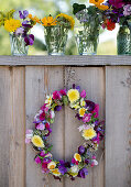 Wreath of flowers and bouquets in water glasses on a wooden fence