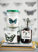 Labels with butterfly motif on screw-top jars with coffee, sugar, and tea