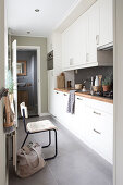 Schmale Küche mit weißer Küchenzeile und Naturdeko, Blick ins Bad