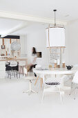 Runder Tisch mit verschiedenen Stühlen in weißem, offenem Wohnraum