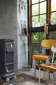 An old wood-burning stove and stacks of chairs in a glass house