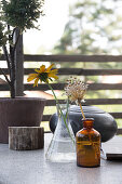 Flowers in glass jars and bottles on an outdoor table