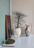 Crystal carafe and ceramic planter with a little tree and on a shelf