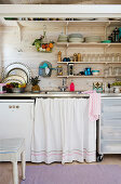 Vorhang vor dem Spülbecken in einer kleinen Küche mit offenen Regalen