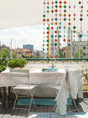 A colourful bead curtain at a garden table with a view of the city