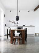 Stools and black chairs at a dining table in front of white kitchen unit