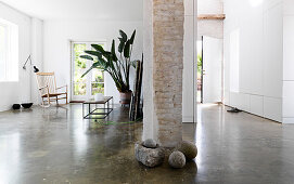 Stones around the brick chimney in open living space with concrete floor
