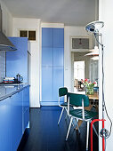 Retro chairs and designer lamps in the dine-in kitchen with blue fronts
