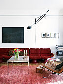 Rotes Retrosofa im Wohnzimmer mit rotem Teppich und Wandleuchte