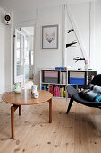 Coffeetable, schwarzer Designerstuhl und halbhohes Regal im Wohnzimmer