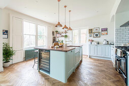 Herringbone parquet floor and island counter in open-plan kitchen in country-house style