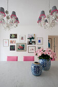 Roses in Chinese vases on table below chandeliers with lampshades