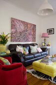 Black leather sofa below painting in colourful living room