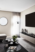 Fernseher über Lowboard und Couchtisch-Set in elegantem Wohnzimmer, runder Spiegel an der Wand