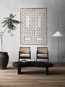 Organisch geformter Couchtisch, zwei Stühle, Stehleuchte und Zimmerpflanze, an Wand moderne Kunst
