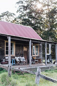 Rustikale Holzhütte mit Veranda, verwittertem Zaun und Wald