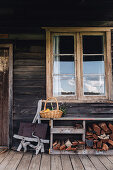 Regal mit Feuerholz unterm Sprossenfenster auf der Veranda