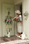 Haustüre mit Ordnungshelfer und Utensilien, Frau hält Korb mit Rosenblüten