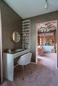 Dressing table against glittery wallpaper and view of bookcase in girl's bedroom
