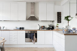 Modern kitchen-dining room with white cabinets and wall units