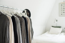 Kleiderung auf Bügeln an einem Garderobenständer im Schlafzimmer