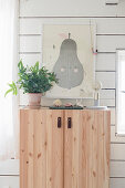 Cute picture of pear above wooden cabinet with leather strap handles