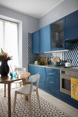 Round dining table and blue kitchen cabinets in kitchen-dining room
