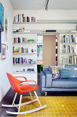 Couch und Designer-Schaukelstuhl in Wohnraum mit deckenhohen Bücheregalen