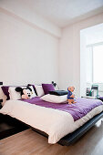 Modernes offenes Schlafzimmer mit Doppelbett und violett-weißer Bettwäsche