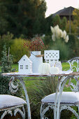 Weisser Sitzplatz in Shabby Style mit Herbstdekoration im Garten