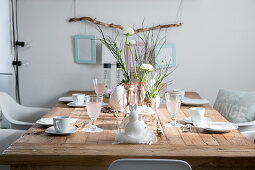 Mit Ranunkeln und weißem Geschirr gedeckter Holztisch zu Ostern