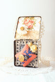 Old tin decorated with wallpaper, everlasting flowers, lace, pin cushion and buttons